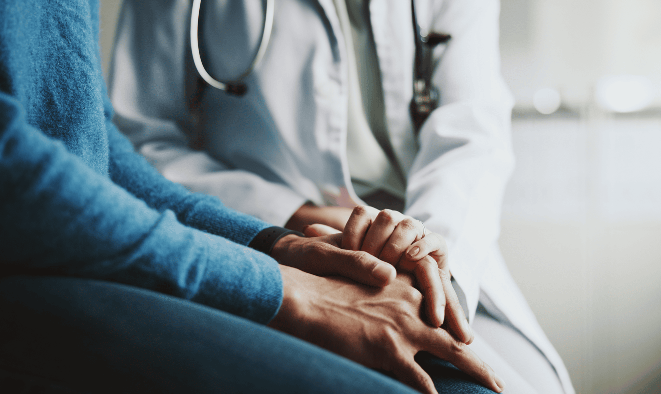 Doctor comforting patient by holding hands